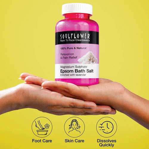 Soulflower Epsom Bath Salt bottle held in cupped hands on a yellow background, highlighting benefits for foot care, skin care, and fast dissolving.