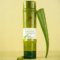 Soulflower Aloe Vera Bamboo Hyaluronic Acid Body Lotion bottle standing beside a fresh aloe vera leaf on a yellow background.