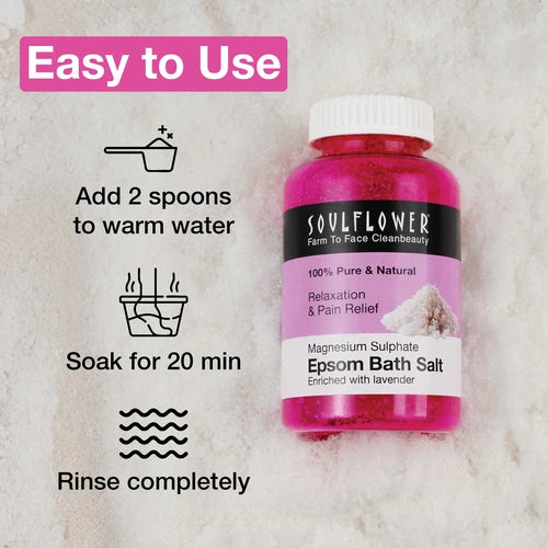Soulflower Epsom Bath Salt bottle with usage instructions—add 2 spoons to warm water, soak for 20 minutes, and rinse completely—shown on a soft pink textured background.