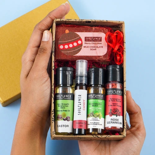 Soulflower Surprise Gift Box featuring Castor Hair Oil, Rosemary Mint Oil, Rose Geranium Oil, Candy Aroma Oil, and Milk Chocolate Soap.